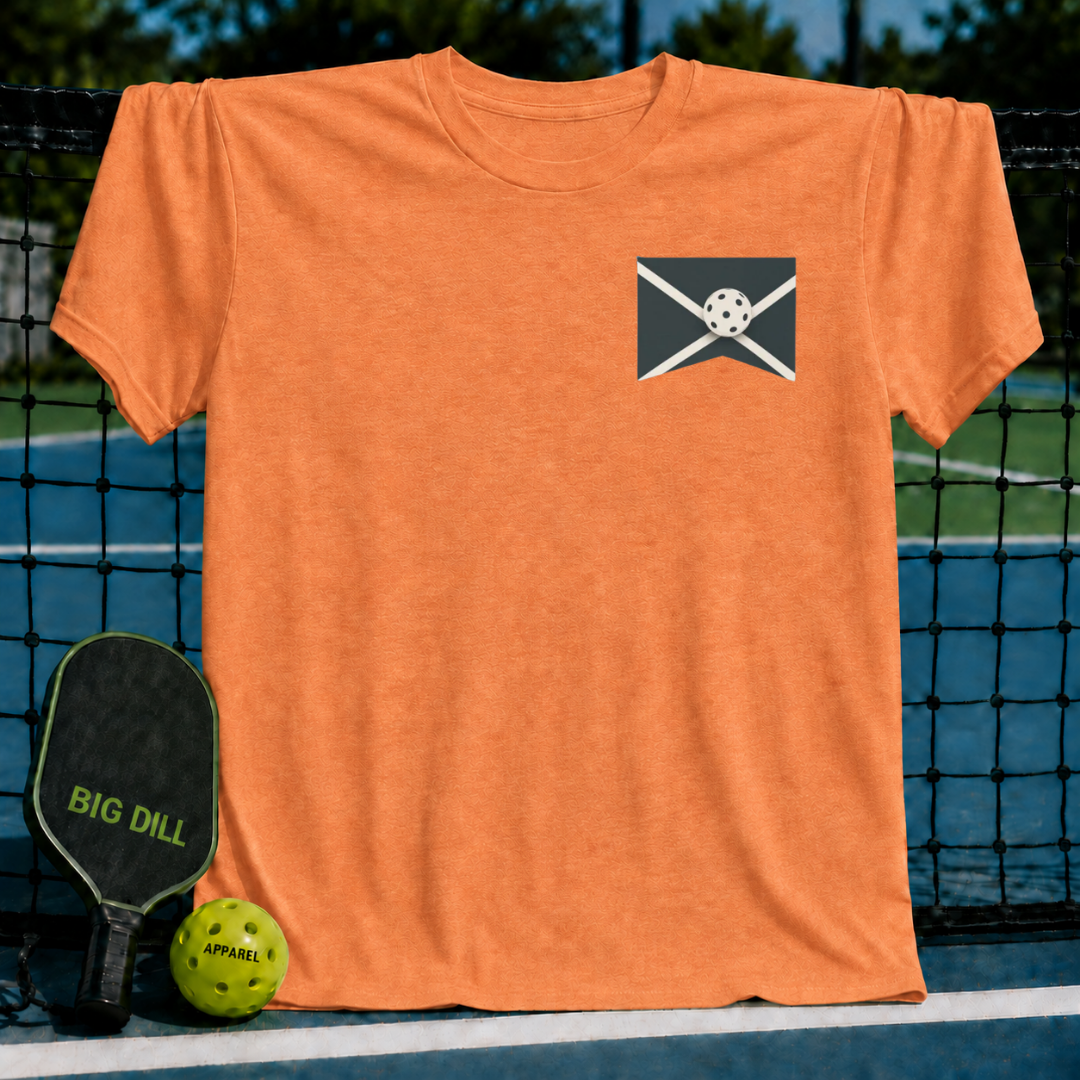 Orange unisex crewneck t-shirt featuring a small pickleball graphic on the chest, displayed against a pickleball court net.