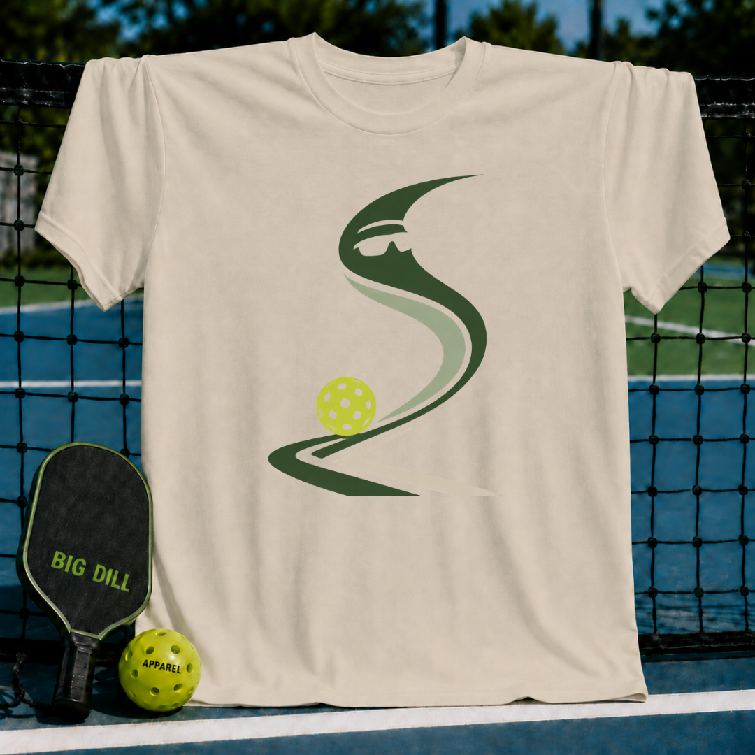 Cream-colored cotton t-shirt featuring a stylized green pickleball graphic, displayed against a pickleball court backdrop.