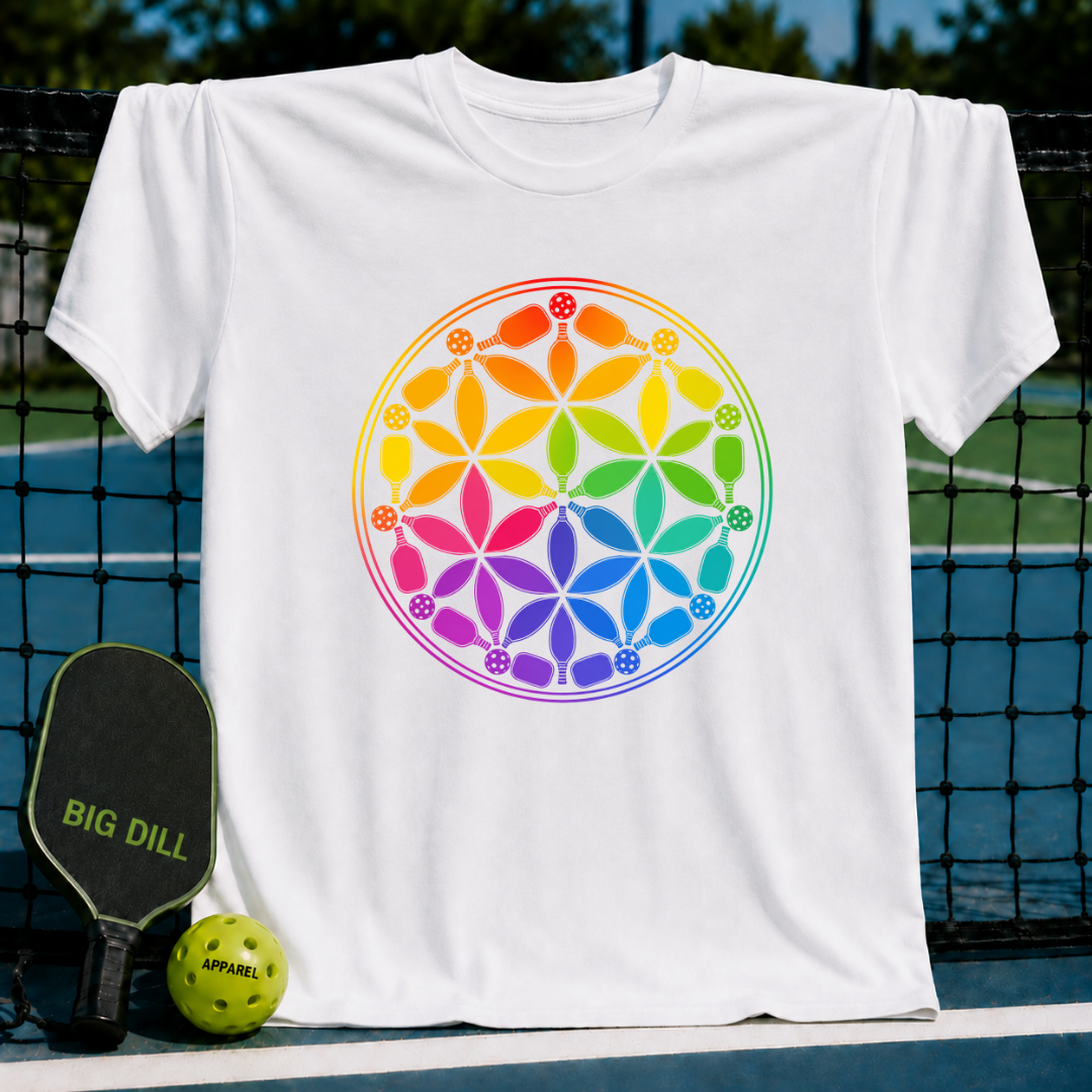 White t-shirt featuring a colorful rainbow Flower of Life design made of pickleball paddles and balls on a court background.
