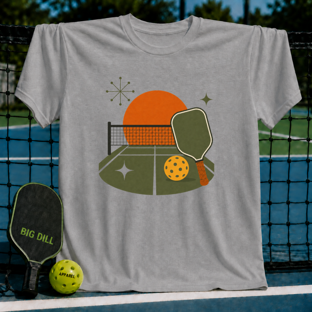 Grey t-shirt featuring a midcentury modern pickleball court graphic with a sunset, paddle, and ball on a court background.