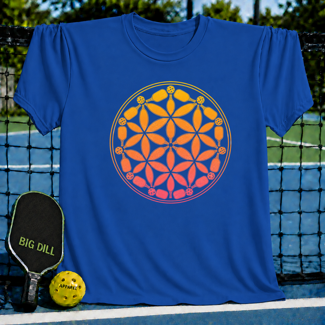 Blue t-shirt featuring an orange and yellow Flower of Life design made of pickleball paddles and balls on a court background.