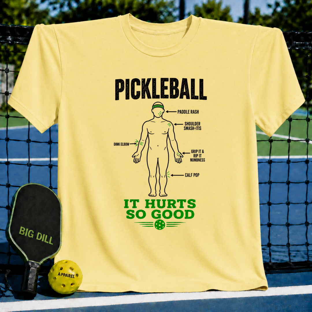 Light yellow crewneck t-shirt featuring a humorous pickleball injury diagram graphic in black and green ink.