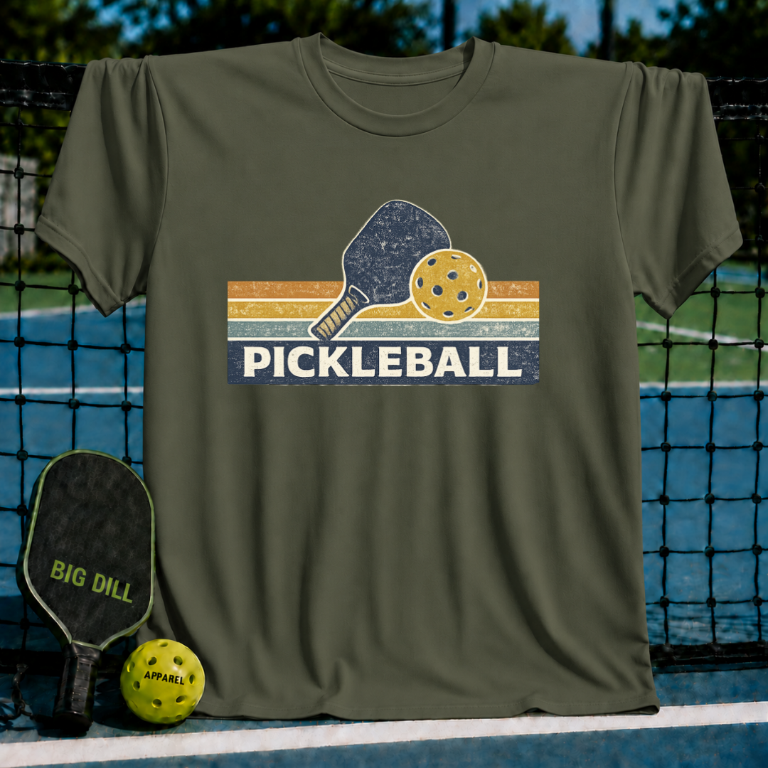 Olive green vintage-style pickleball t-shirt featuring a retro paddle and ball graphic on a court background.
