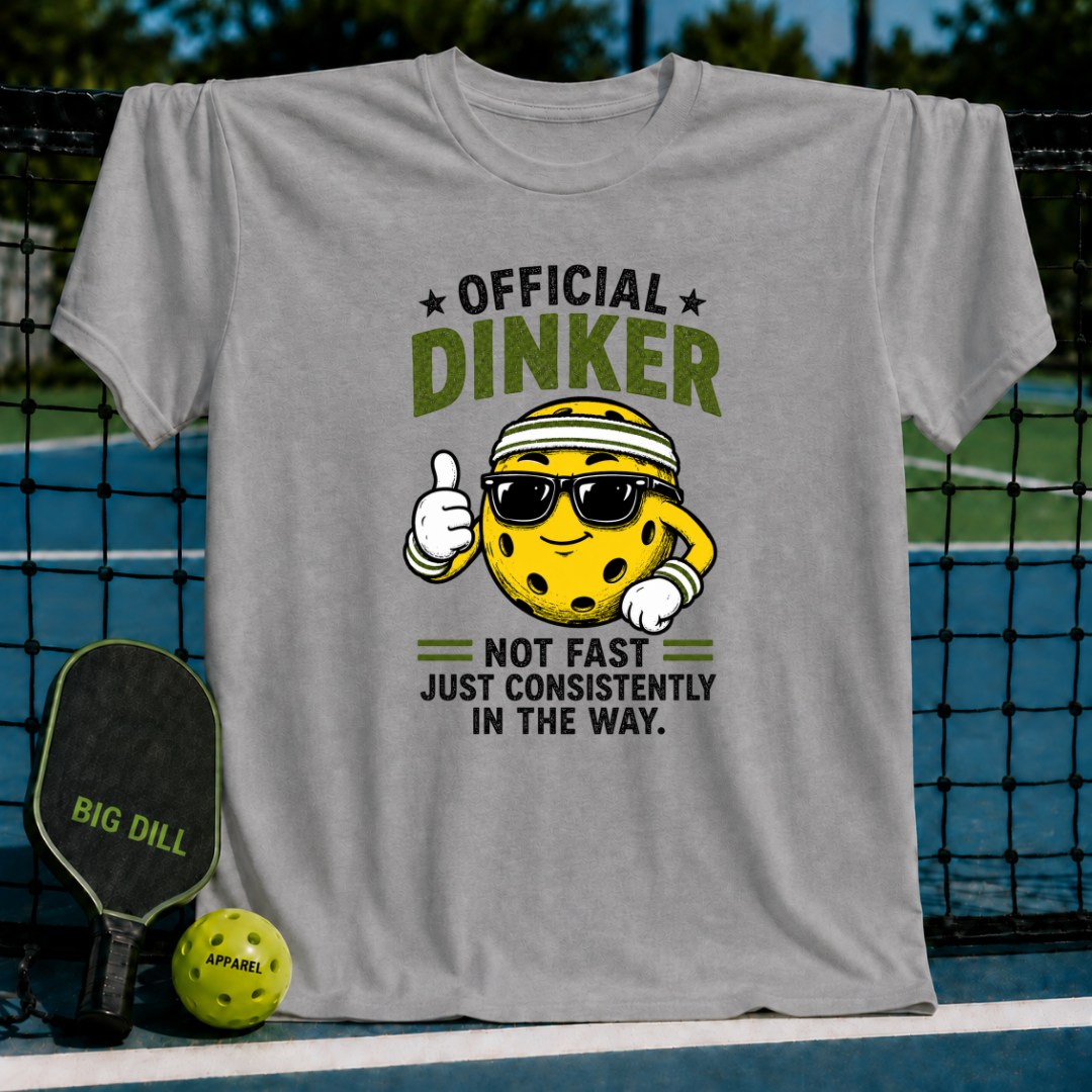 Grey crewneck t-shirt featuring a cartoon pickleball character with sunglasses and the text Official Dinker on a court.