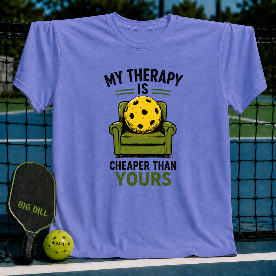Periwinkle unisex t-shirt featuring a graphic of a pickleball sitting in a green armchair with the text My Therapy Is Cheaper.
