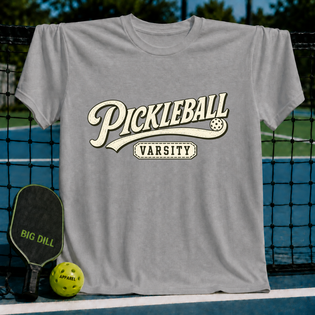 Grey crewneck t-shirt featuring a vintage-style Pickleball Varsity graphic with a pickleball icon on a court background.
