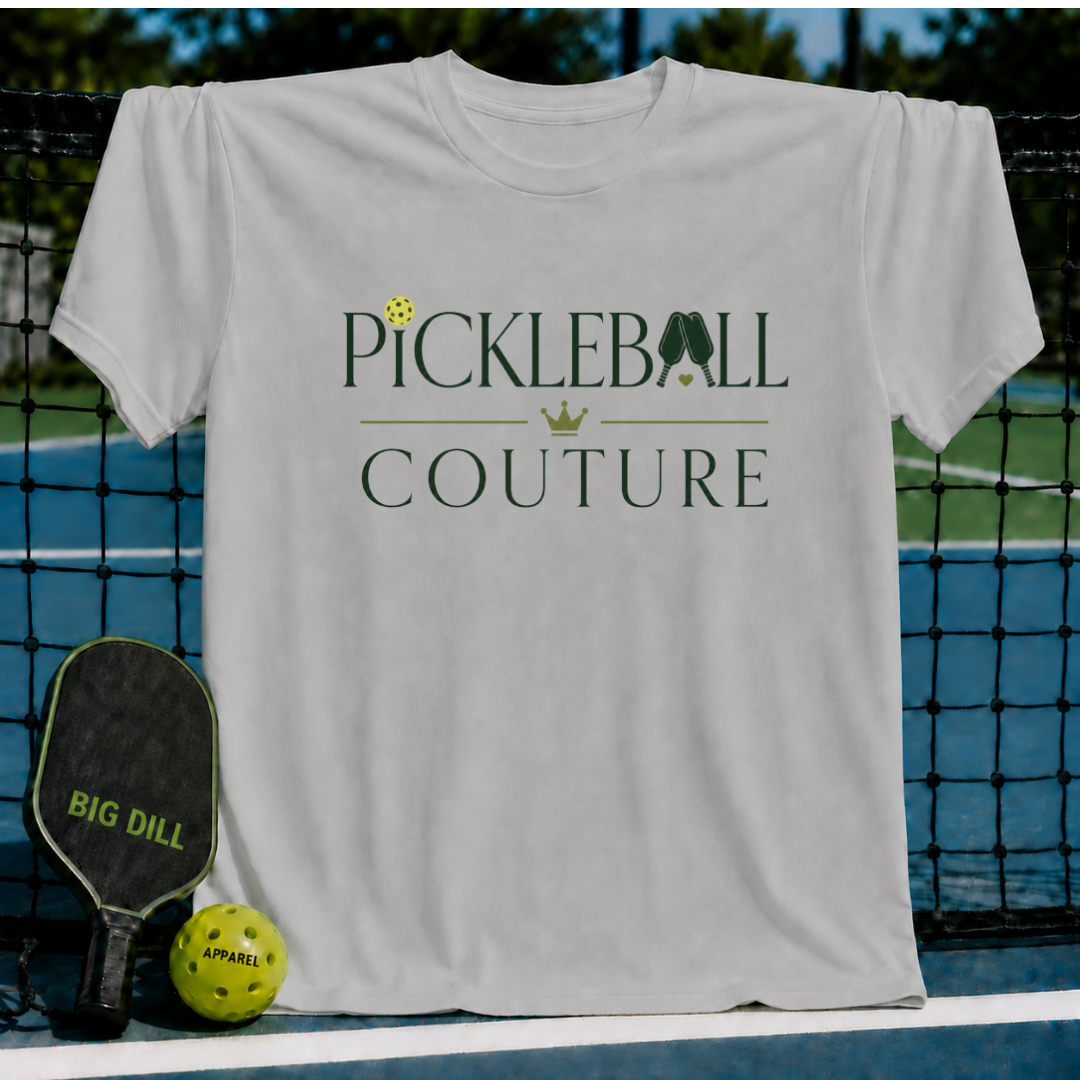 Light gray unisex t-shirt featuring dark green Pickleball Couture typography, a gold crown, and pickleball graphic.