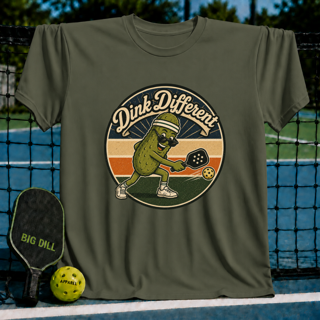 Olive green unisex t-shirt featuring a retro pickleball graphic of a pickle in a visor hitting a ball with a paddle.