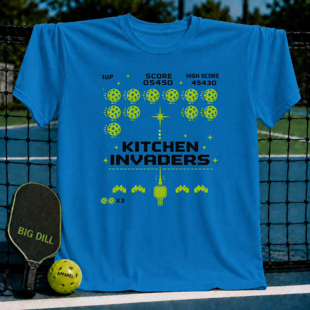 Blue unisex t-shirt featuring a neon green pixel-art arcade game graphic with pickleballs and a paddle design.