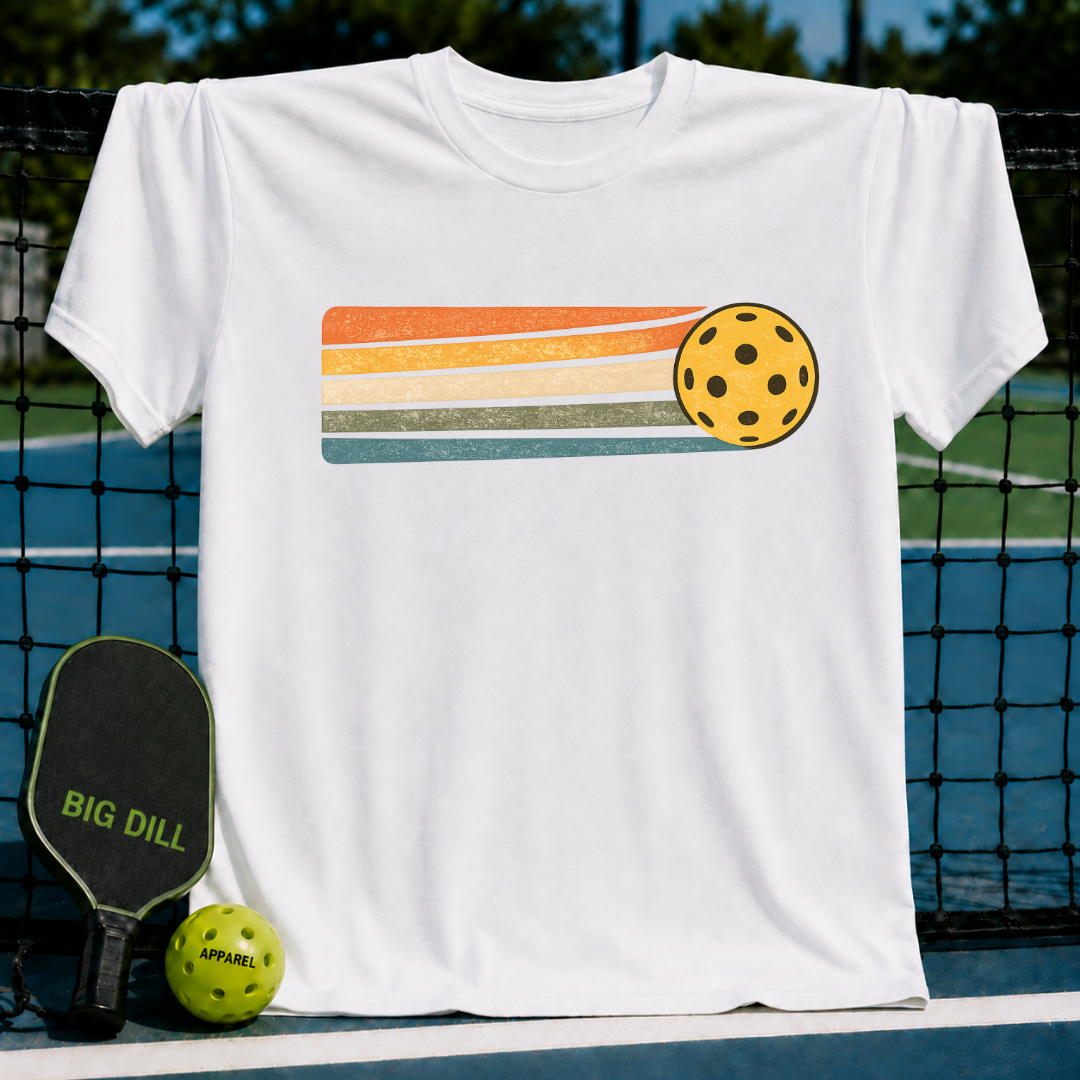 White unisex t-shirt featuring a retro yellow pickleball graphic with orange, cream, and teal motion stripes on a court.