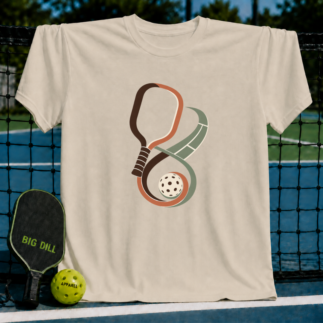 Beige cotton t-shirt featuring an infinity-shaped pickleball paddle and court graphic with a ball on a court background.