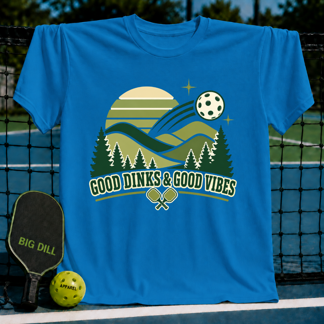 Bright blue crew neck t-shirt featuring a retro pickleball landscape graphic with the text Good Dinks & Good Vibes.