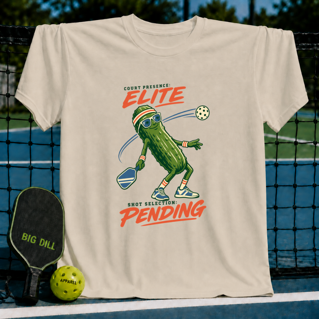 Cream-colored cotton t-shirt featuring a cartoon pickle playing pickleball with the text Court Presence Elite.