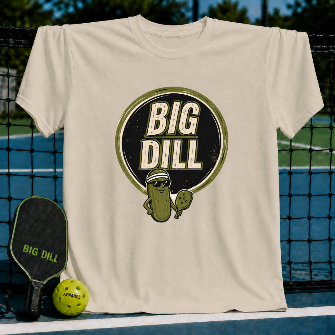 Beige crewneck T-shirt featuring a Big Dill pickle graphic with sunglasses and a pickleball paddle on a court.