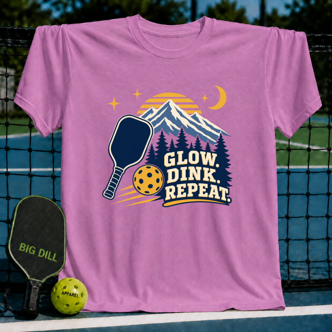 Pink cotton t-shirt featuring a mountain, pickleball paddle, and ball graphic with the text Glow, Dink, Repeat.