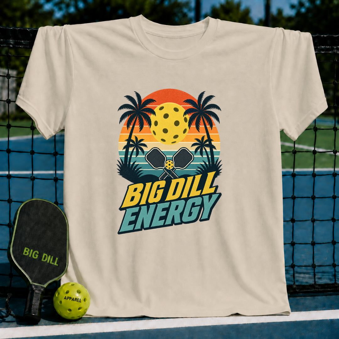 Beige crewneck t-shirt featuring a retro sunset, palm trees, and pickleball graphic with Big Dill Energy text.
