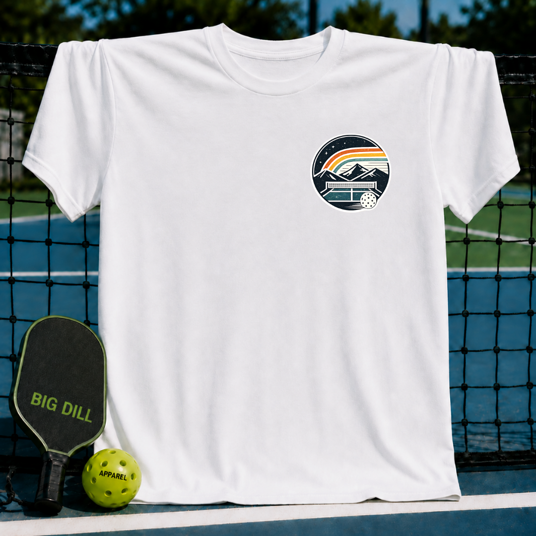 White unisex t-shirt featuring a circular pickleball crest graphic with mountains, a rainbow, and a court on a pickleball net.