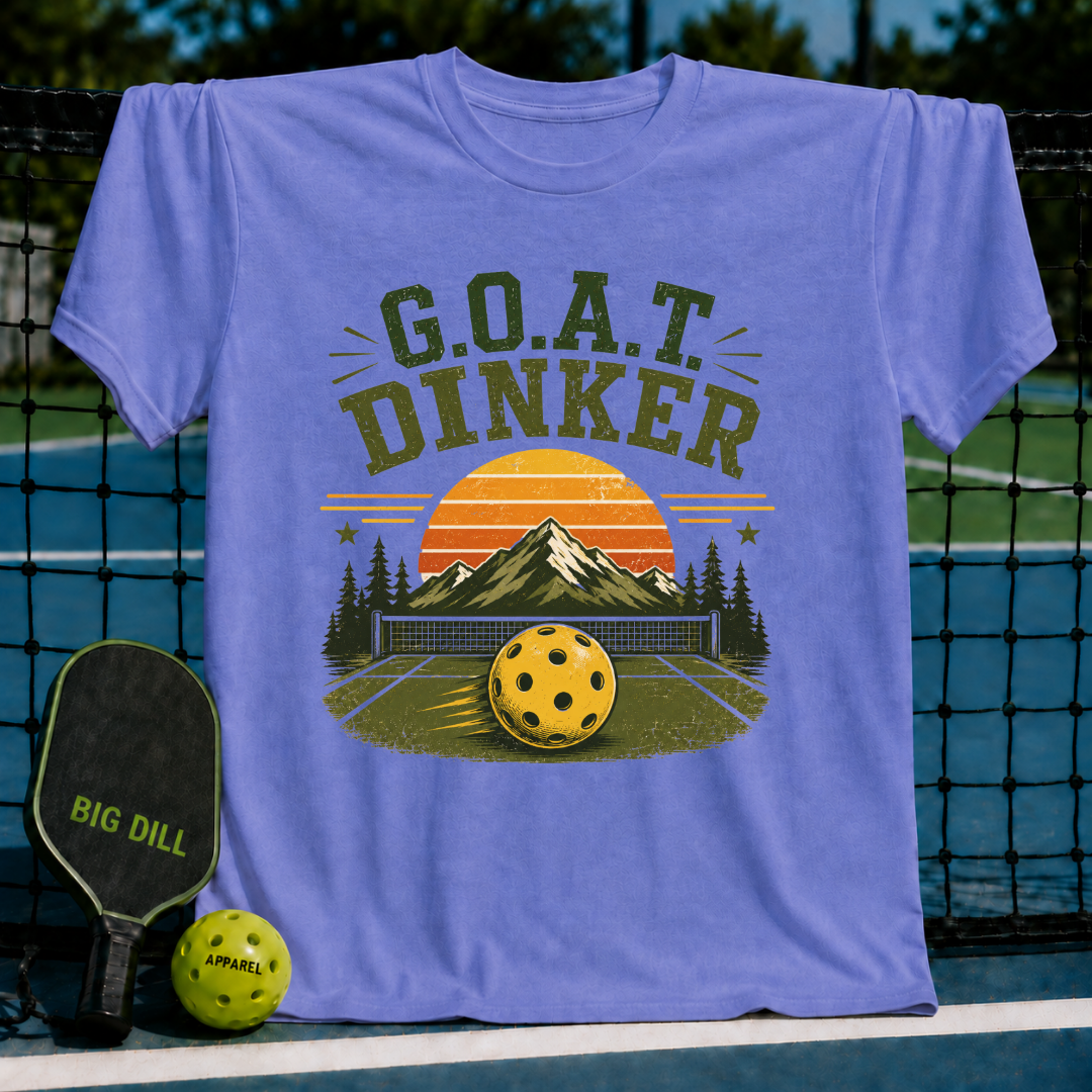Periwinkle blue unisex t-shirt featuring a retro pickleball sunset landscape graphic with G.O.A.T. DINKER text.