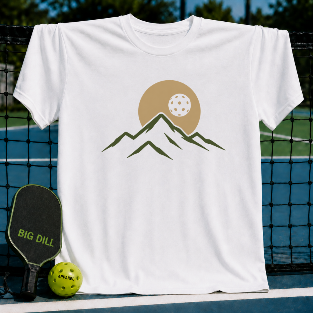 White unisex t-shirt featuring a minimalist mountain and pickleball eclipse graphic in earth tones on a pickleball court.