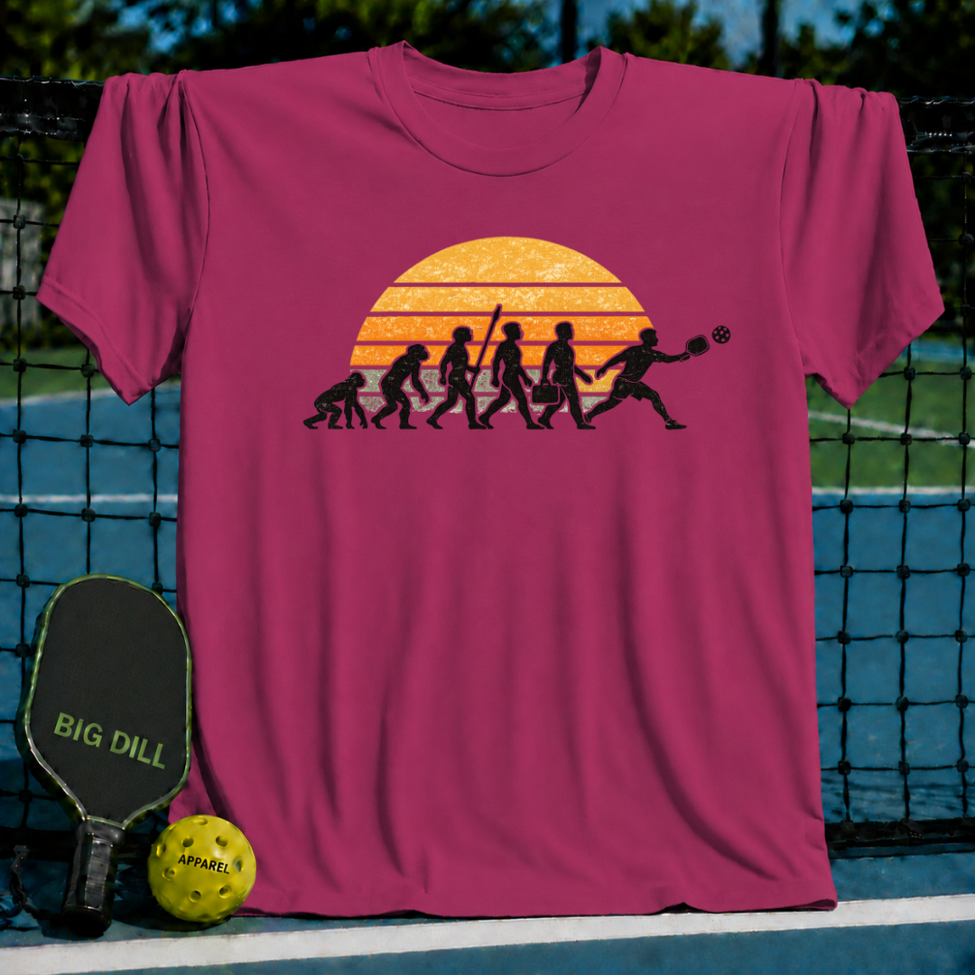 Maroon unisex t-shirt featuring a retro sunset and human evolution graphic showing a man playing pickleball.