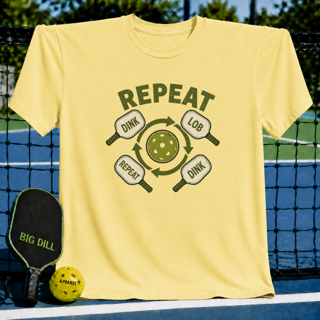 Light yellow crew neck t-shirt featuring a green pickleball graphic with dink, lob, and repeat text on a court background.