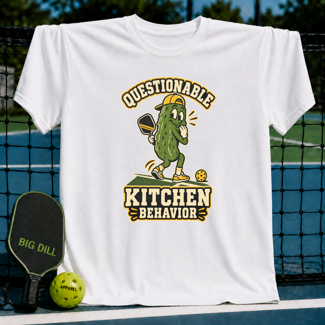 White cotton t-shirt featuring a cartoon pickle playing pickleball with the text Questionable Kitchen Behavior.