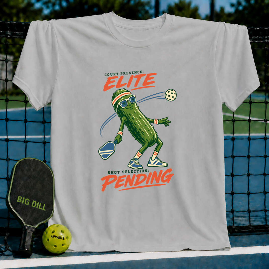 Light gray crewneck t-shirt featuring a pickleball-playing pickle graphic with sunglasses and text on a pickleball court.