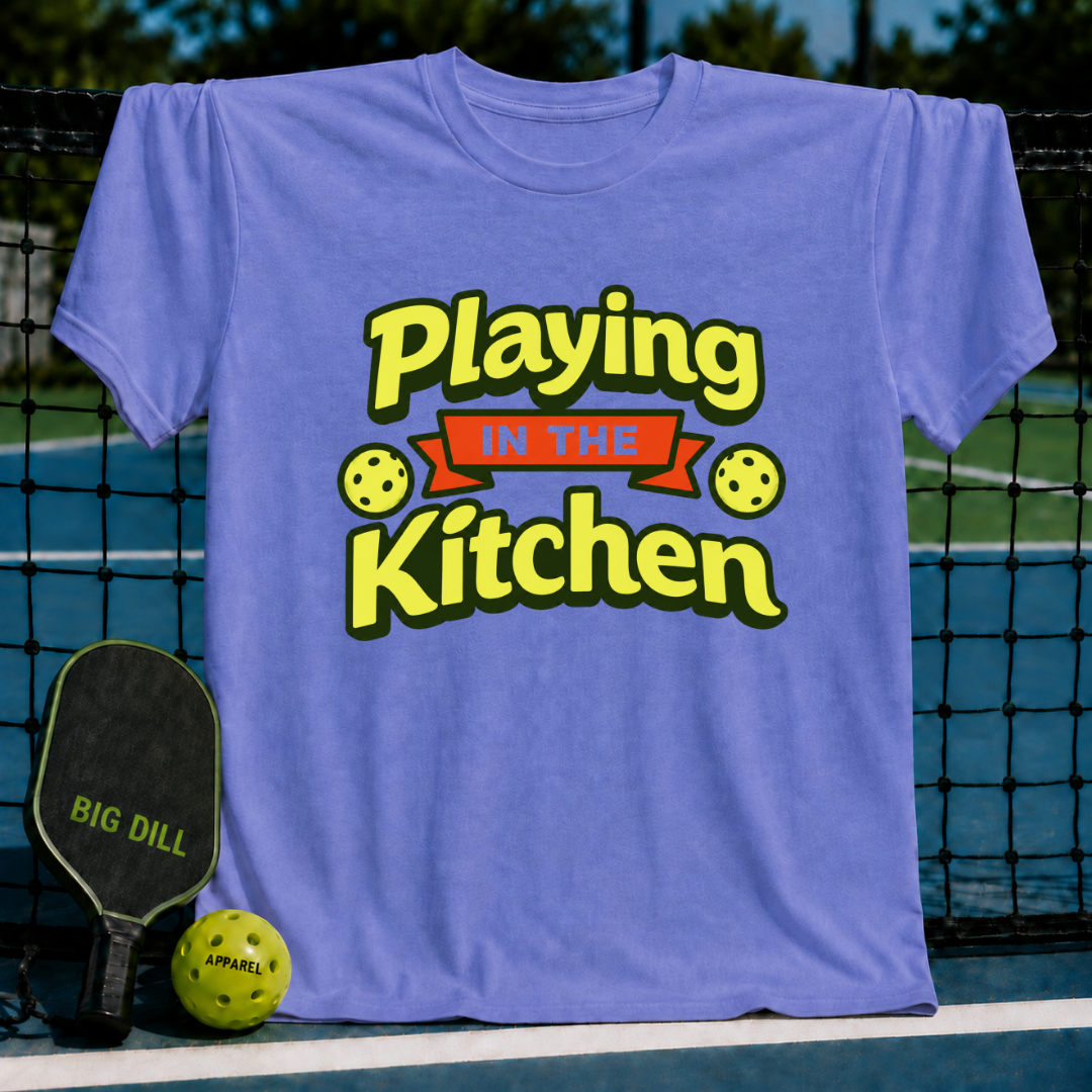 Periwinkle blue crewneck t-shirt featuring a yellow and red Playing in the Kitchen pickleball graphic on a court.