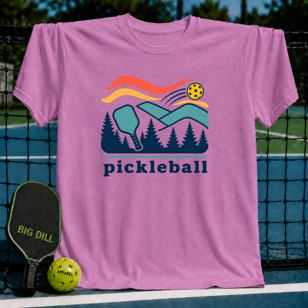Pink cotton t-shirt featuring a colorful pickleball court and forest graphic with the word pickleball printed below.