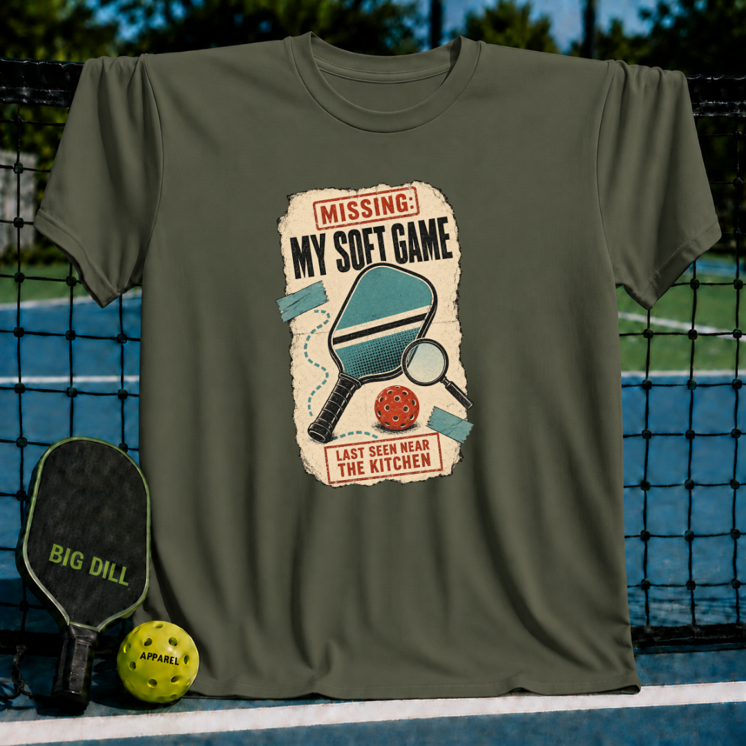 Olive green crewneck t-shirt featuring a vintage-style Missing My Soft Game pickleball graphic on a court background.