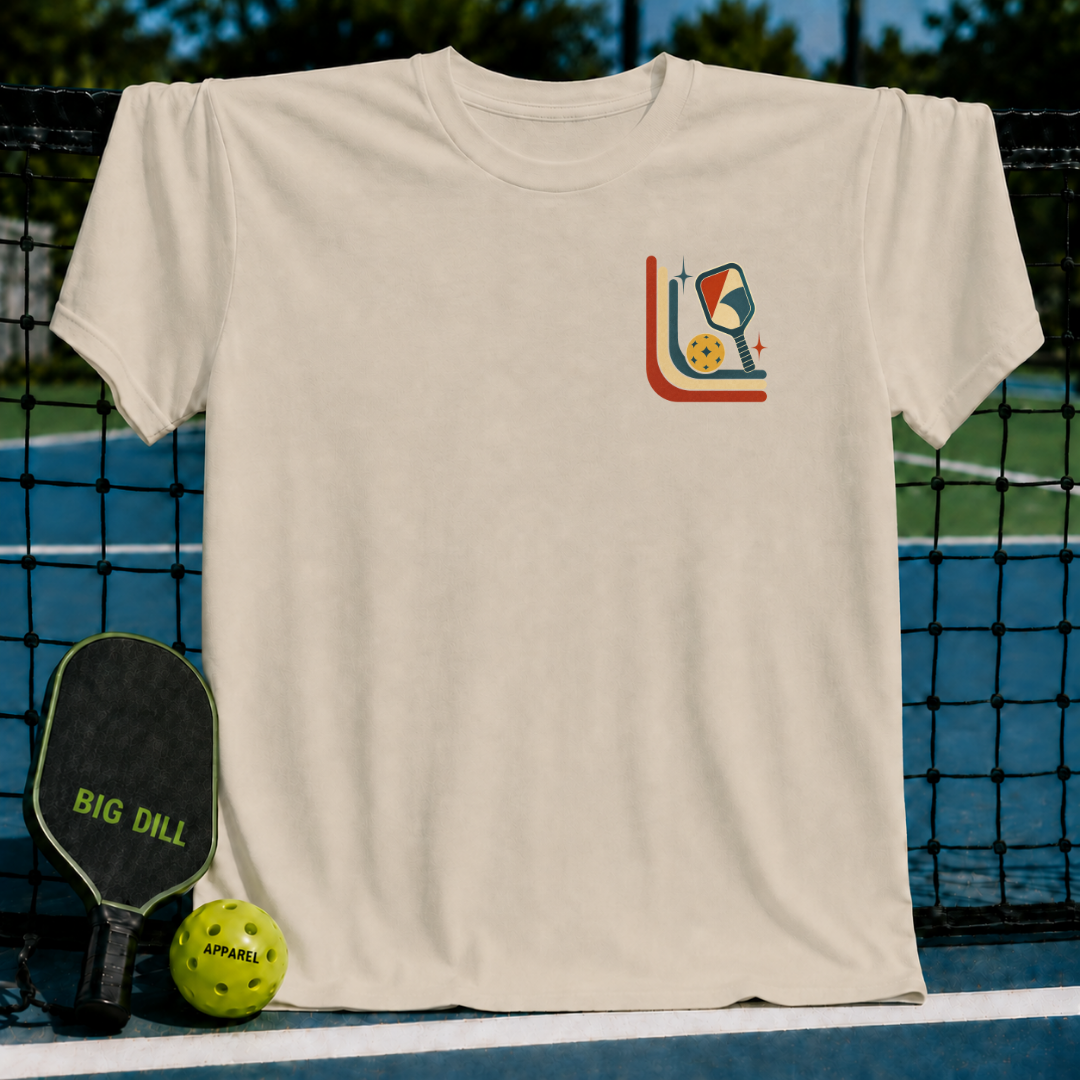 Beige unisex t-shirt featuring a mid-century retro pickleball graphic with stars and curves, displayed on a pickleball court.