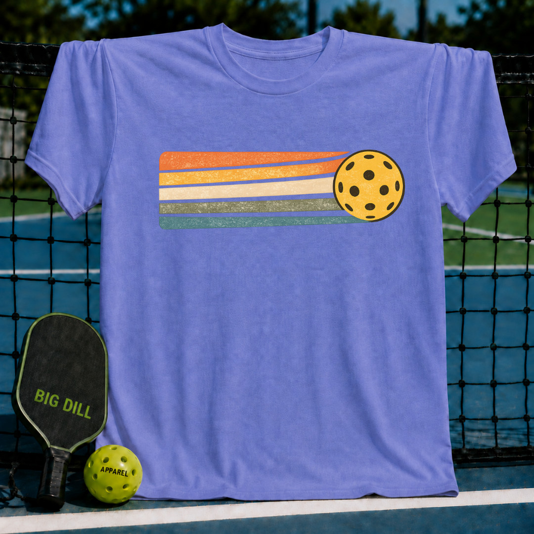 Periwinkle blue unisex t-shirt featuring a retro sunset stripe graphic and a yellow pickleball on a pickleball court.