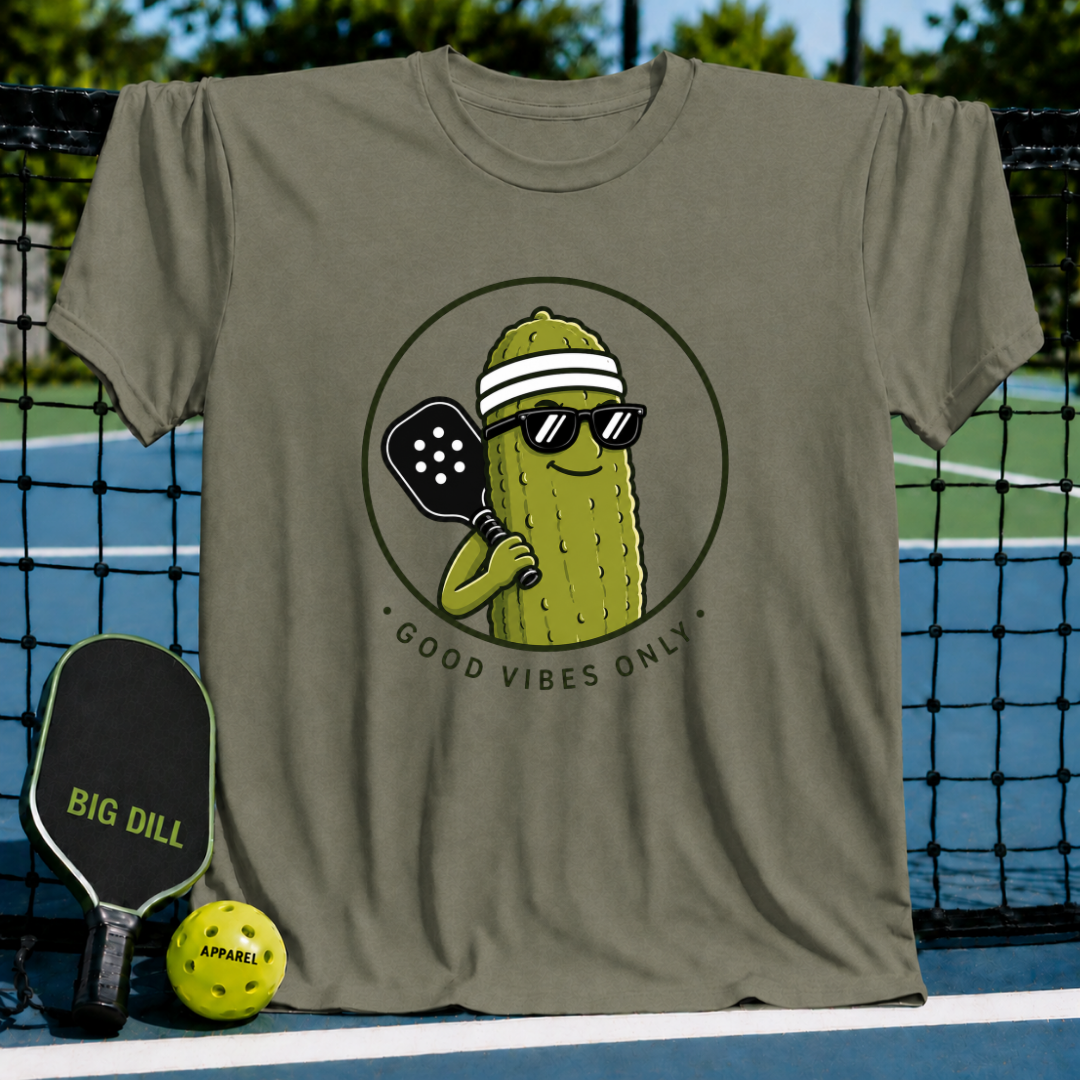 Olive green unisex t-shirt featuring a smiling pickle character with sunglasses, a visor, and a pickleball paddle.