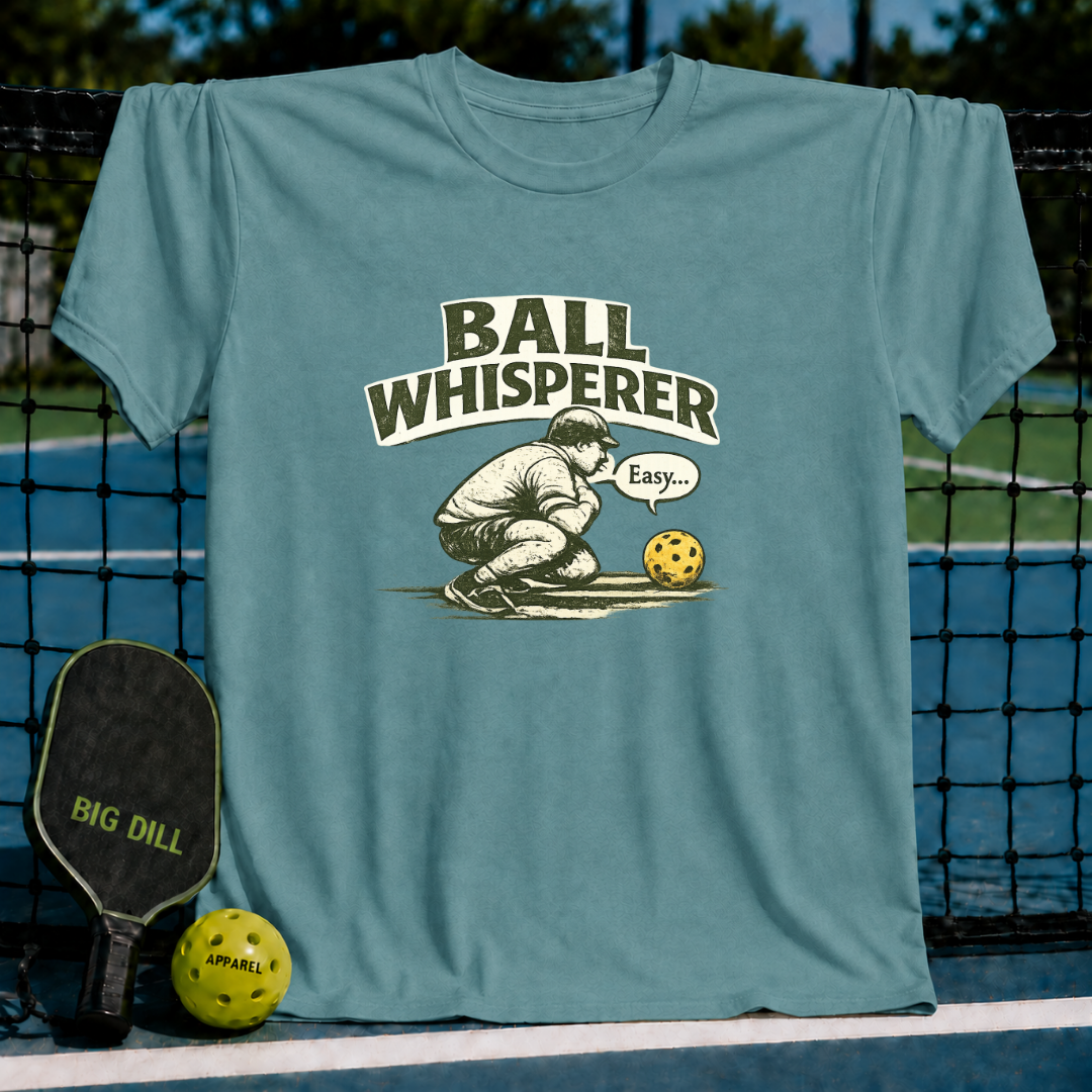 Blue-grey unisex t-shirt featuring a vintage Ball Whisperer illustration of a player crouching by a pickleball.