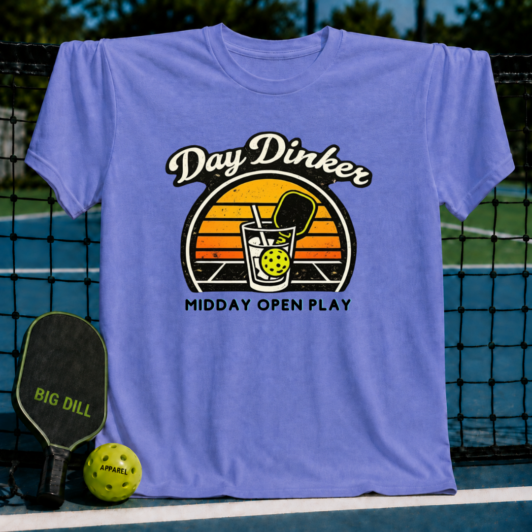 Periwinkle blue unisex t-shirt featuring a retro sunset graphic of a pickleball paddle and ball in a glass.