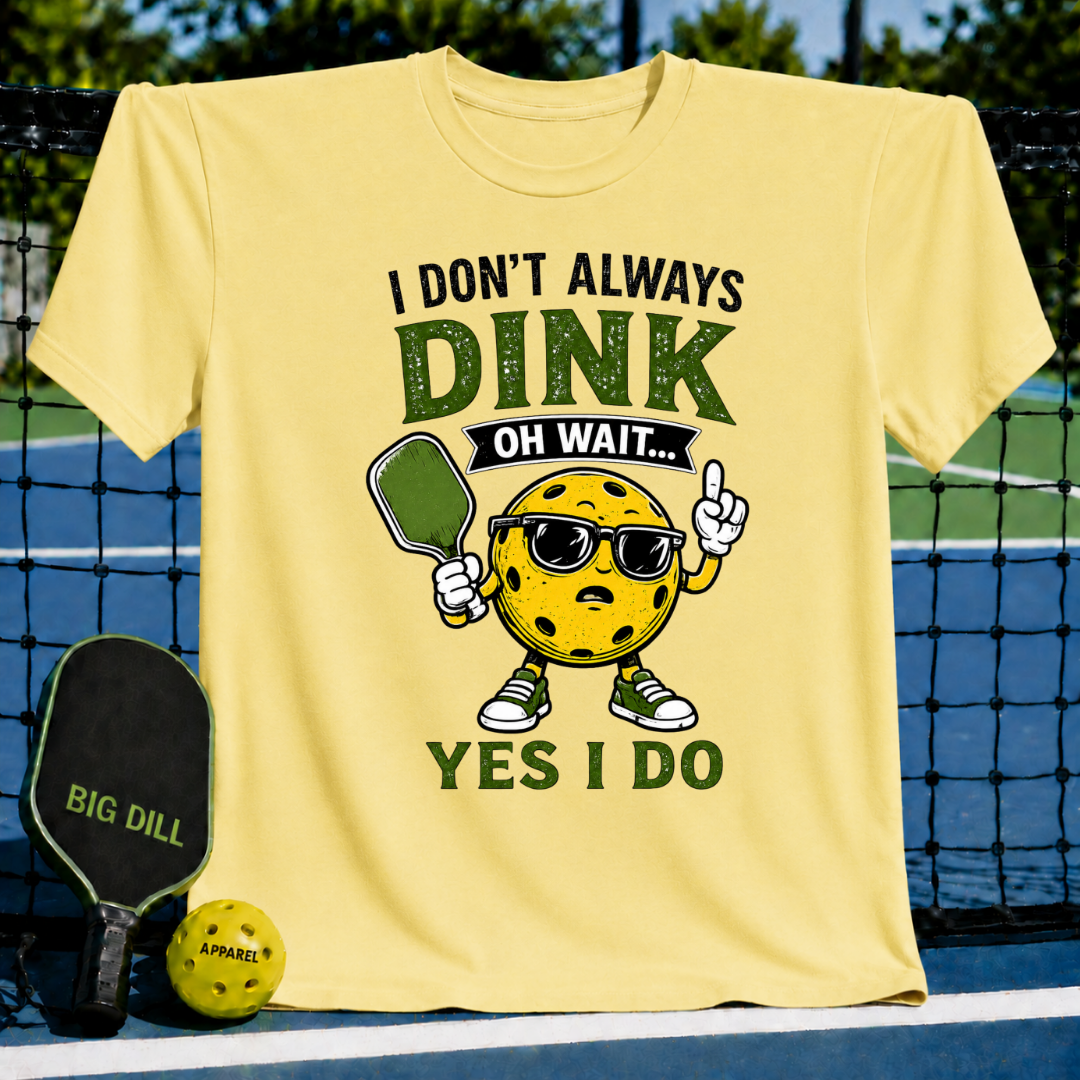 Light yellow crew neck t-shirt featuring a pickleball-themed graphic with a cartoon ball wearing sunglasses and holding a paddle.