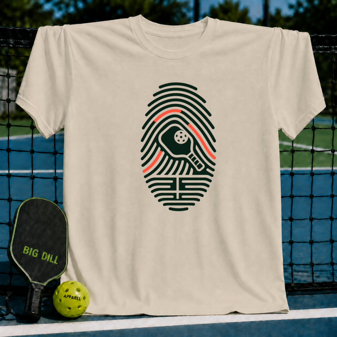 Beige crew neck t-shirt featuring a dark green fingerprint graphic with a pickleball paddle and ball icon.
