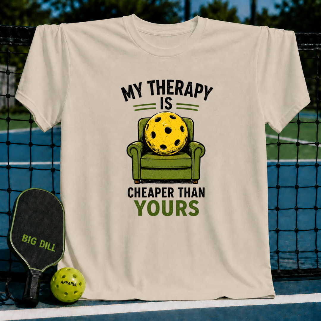 Beige unisex t-shirt featuring a graphic of a yellow pickleball sitting in a green armchair with the text My Therapy Is Cheaper.