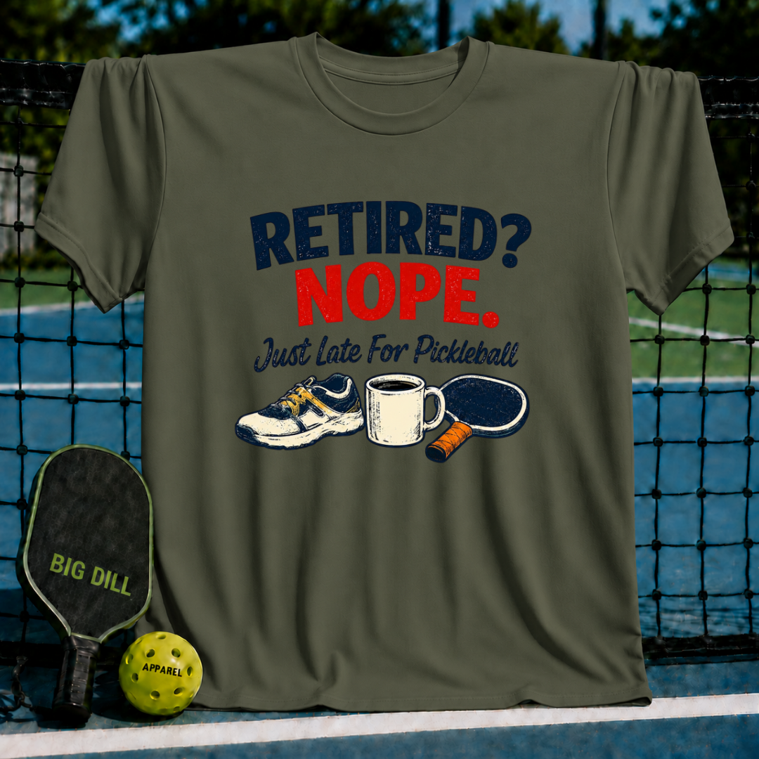Olive green crewneck t-shirt featuring a Retired? Nope. Just Late For Pickleball graphic with a shoe, mug, and paddle.