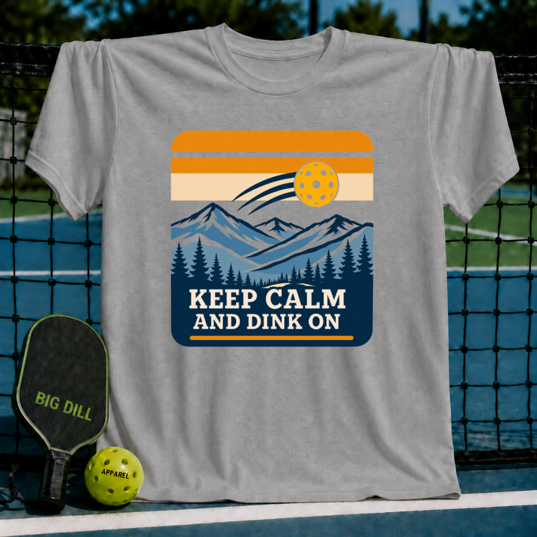 Grey crew neck t-shirt featuring a mountain landscape graphic, pickleball, and the text Keep Calm And Dink On.