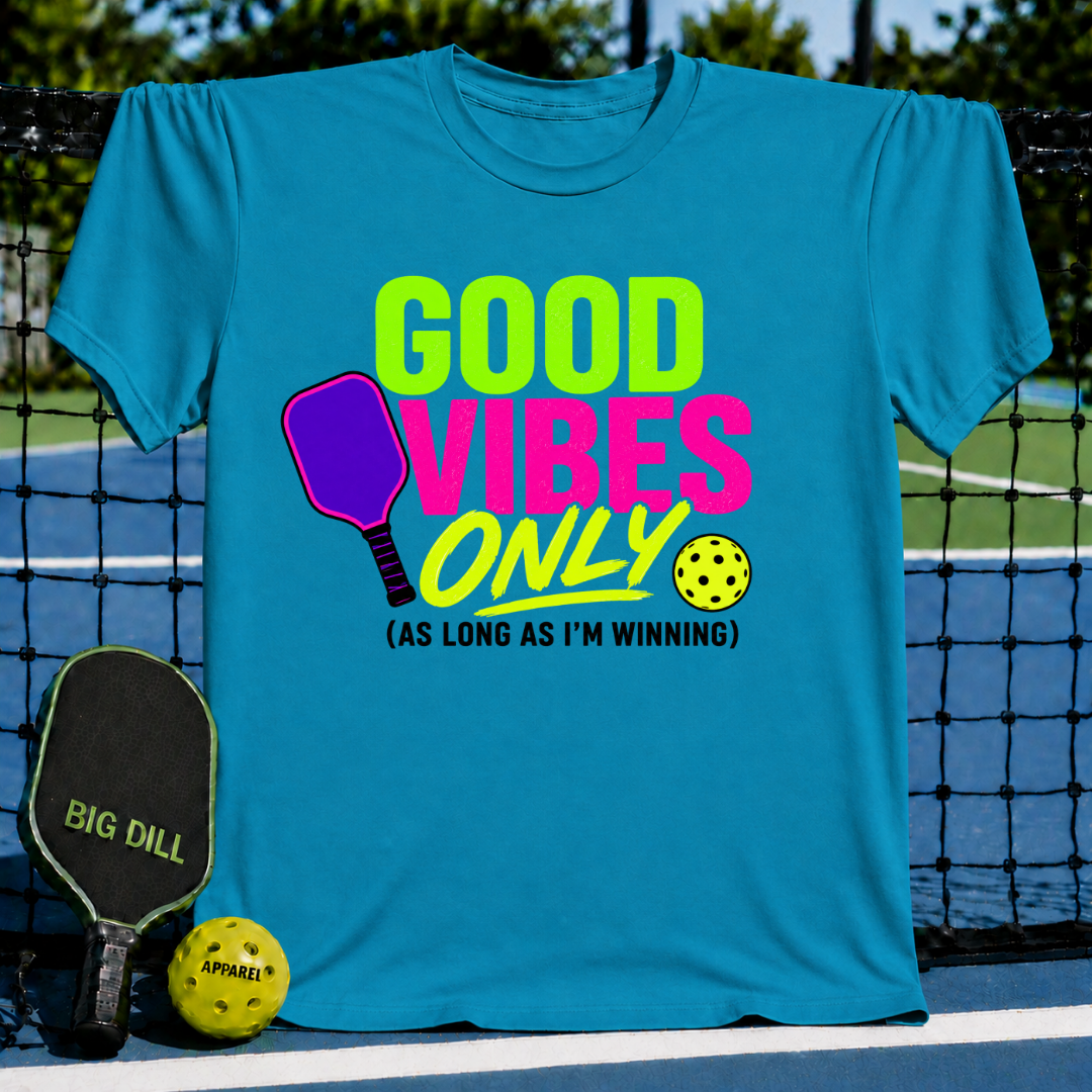 Periwinkle blue unisex t-shirt featuring a neon pink and green pickleball graphic with the text Good Vibes Only.