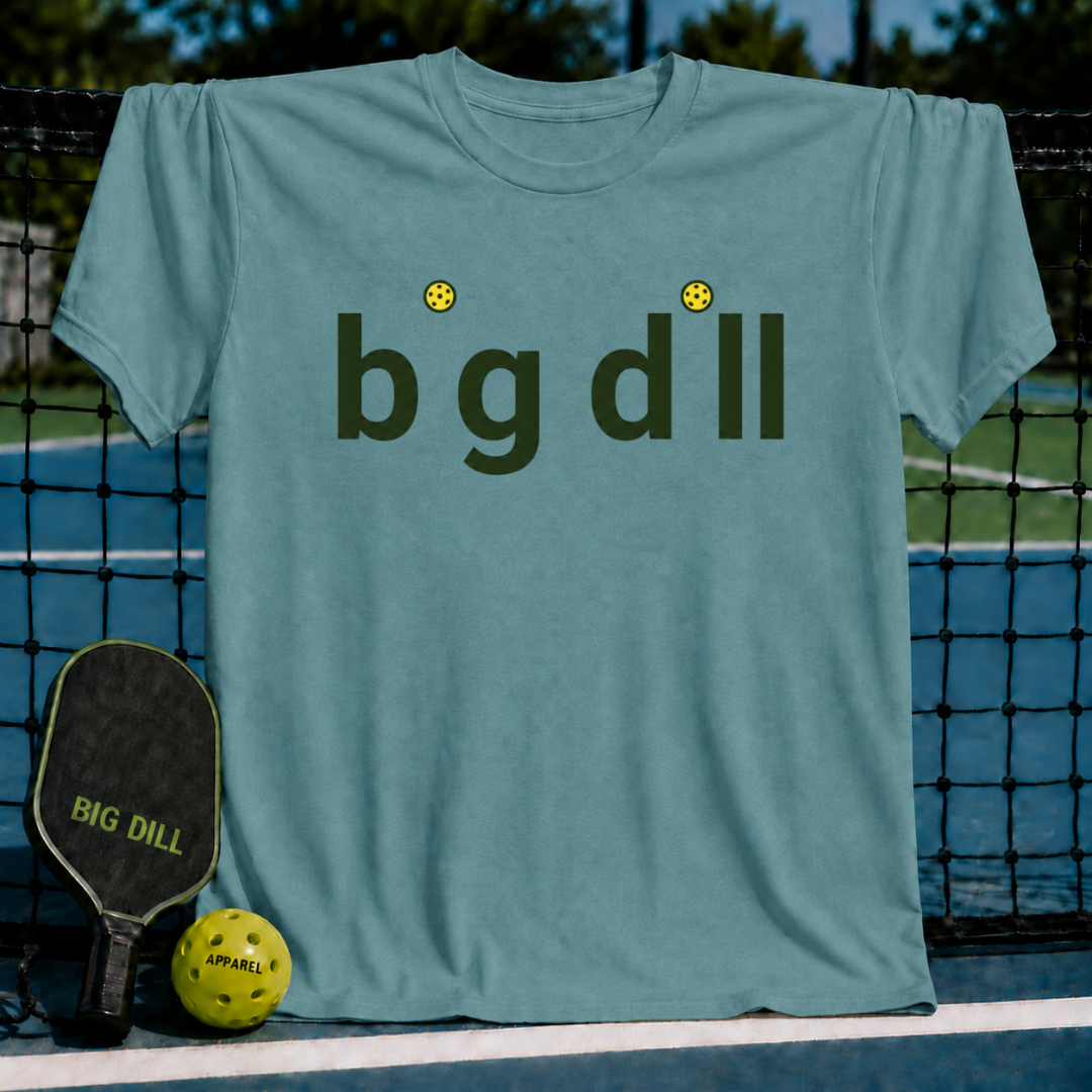 Heather gray unisex t-shirt featuring a Big Dill wordmark with yellow pickleball dots, displayed on a pickleball court.