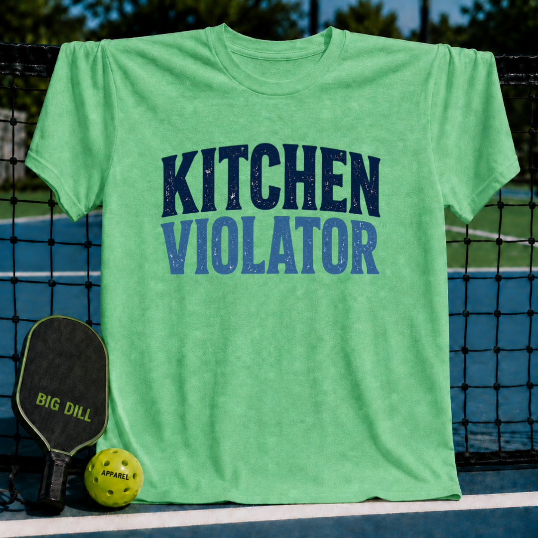 Light green unisex t-shirt with distressed navy Kitchen Violator varsity lettering, displayed on a pickleball court.
