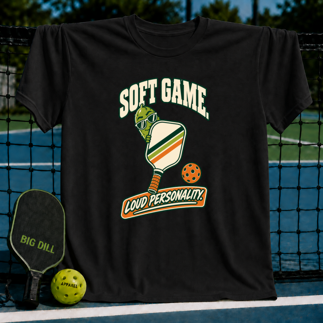 Black cotton t-shirt featuring a pickleball-themed graphic with a pickle wearing sunglasses and the text Soft Game, Loud Personality.