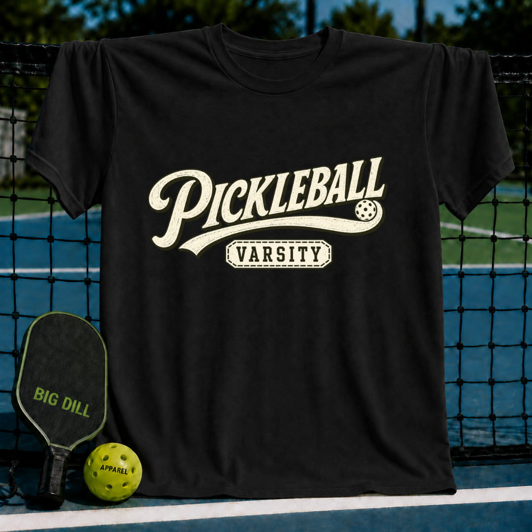 Black crewneck t-shirt featuring a vintage cream-colored Pickleball Varsity graphic on a pickleball court background.
