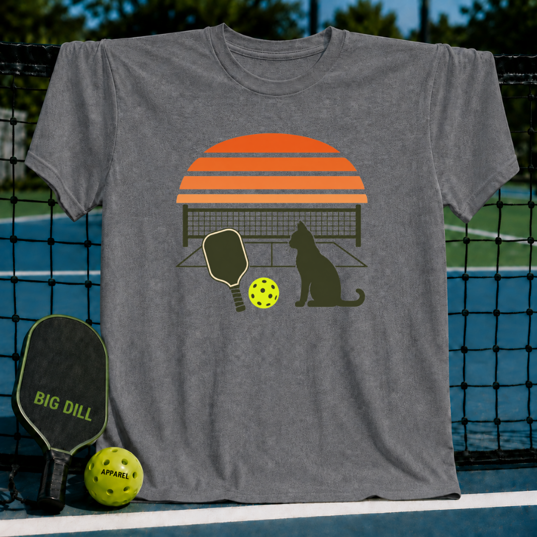 Grey unisex t-shirt featuring a retro orange sunset, cat silhouette, pickleball paddle, and ball graphic.