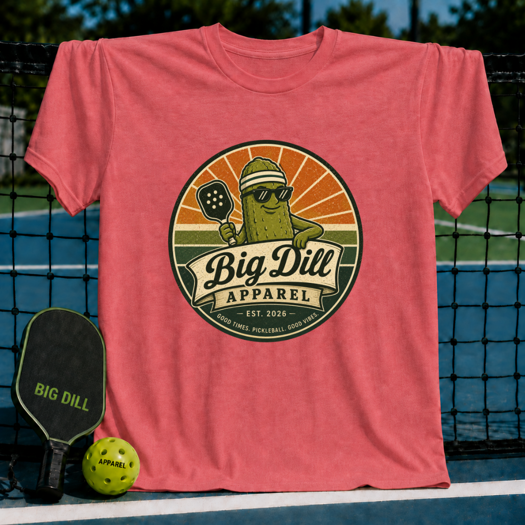 Coral pink unisex t-shirt featuring a retro pickleball mascot graphic with sunglasses and a paddle on a pickleball court.