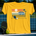 Bright yellow cotton t-shirt featuring a retro van, palm trees, and pickleball court graphic on a court background.