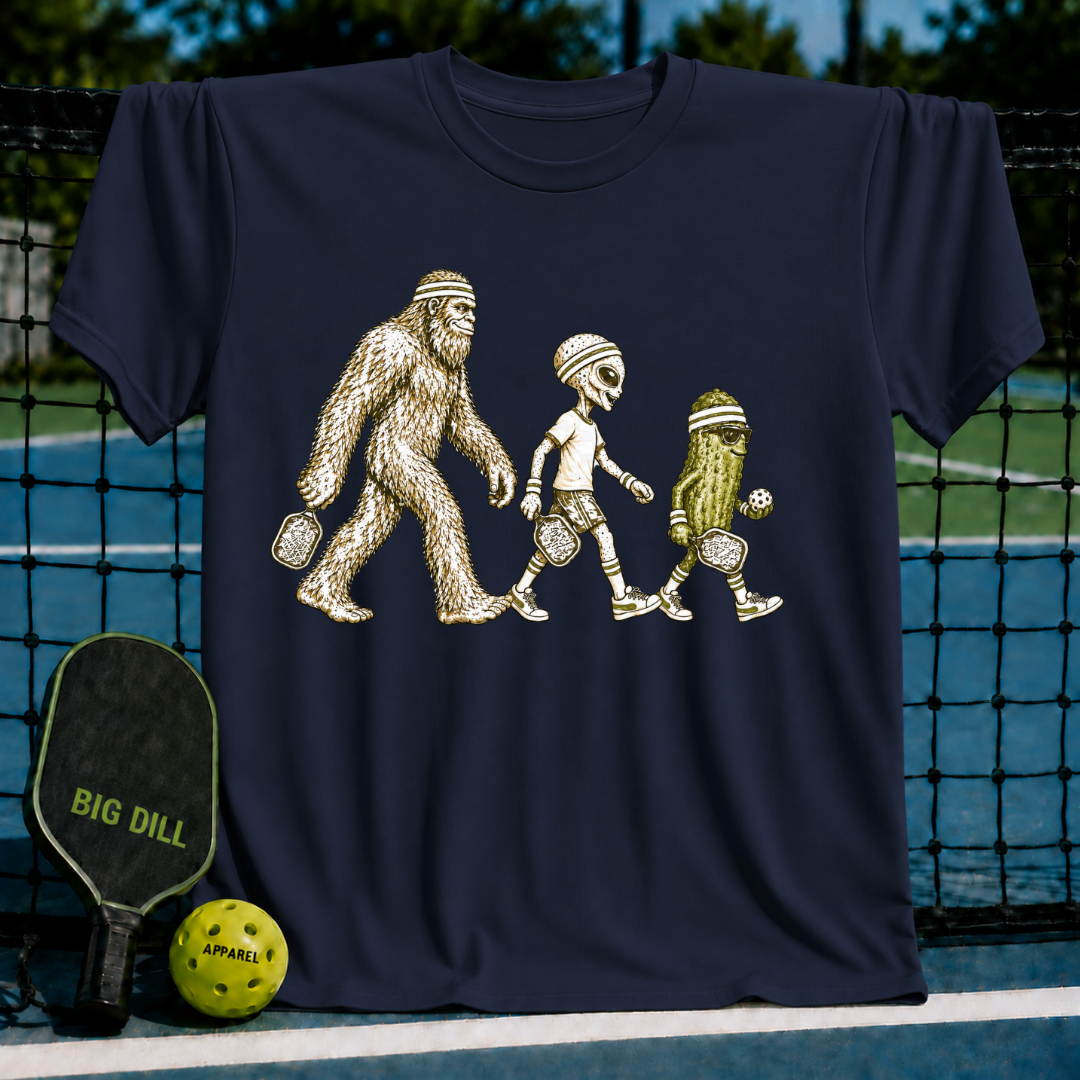 Navy blue crewneck t-shirt featuring a graphic of Bigfoot, an alien, and a pickle playing pickleball on a court.