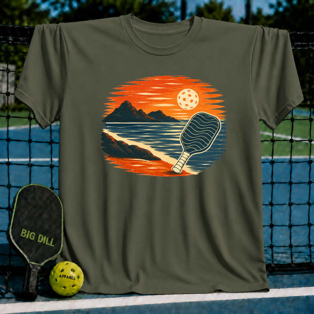 Olive green unisex t-shirt featuring a vintage oval illustration of a pickleball paddle at sunset over mountains.